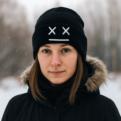 un bonnet à revers noir ou blanc brodé, représentant des yeux en forme de croix et une bouche minimaliste. Design tendance, moderne et minimaliste pour un look urbain street wear adorable.