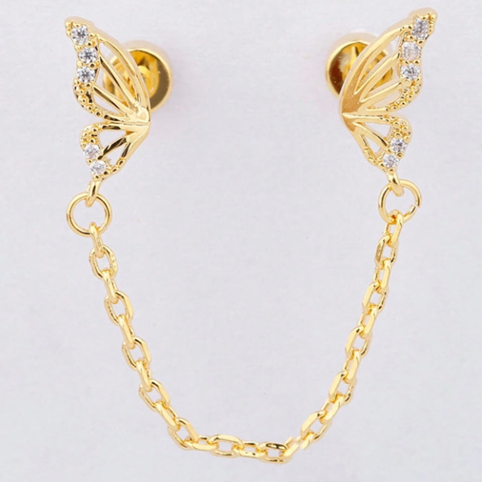 une boucle d'oreilles doré composée de deux papillons dorés tout en strass reliés par une chainette.