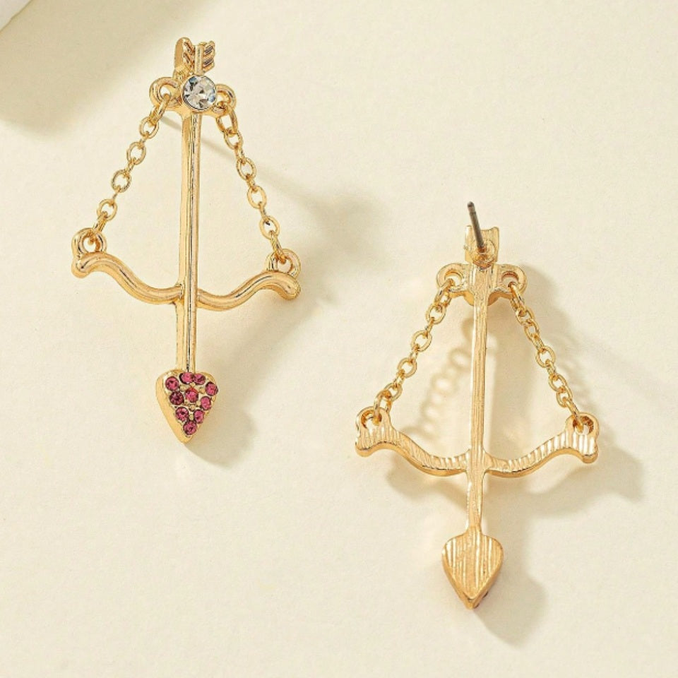 une paire de boucles d'oreilles en forme d'arc de cupidon avec sa flèche à la pointe strass roses