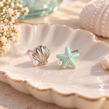 Boucles d’oreilles asymétriques étoile de mer vert pastel et coquillage argenté avec perles, présentées dans un élégant décor estival inspiré de la mer.