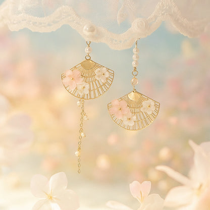 une paire de boucles d'oreilles asymétriques composées d'éventails dorés décorés avec de jolies fleurs de sakura, des perles blanches viennent apporter de l'élégance à l'ensemble.