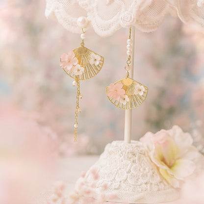 une paire de boucles d'oreilles asymétriques composées d'éventails dorés décorés avec de jolies fleurs de sakura, des perles blanches viennent apporter de l'élégance à l'ensemble.