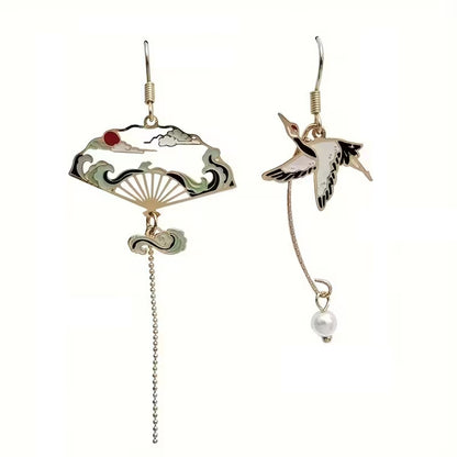 une paire de boucles d'oreilles dorés asymétriques. D'un côté, une grue japonaise et de l'autre, un éventail au motif de la grande vague de Kanagawa. Esthétique qui rappelle les estampes japonaises. Bijou élégant.
