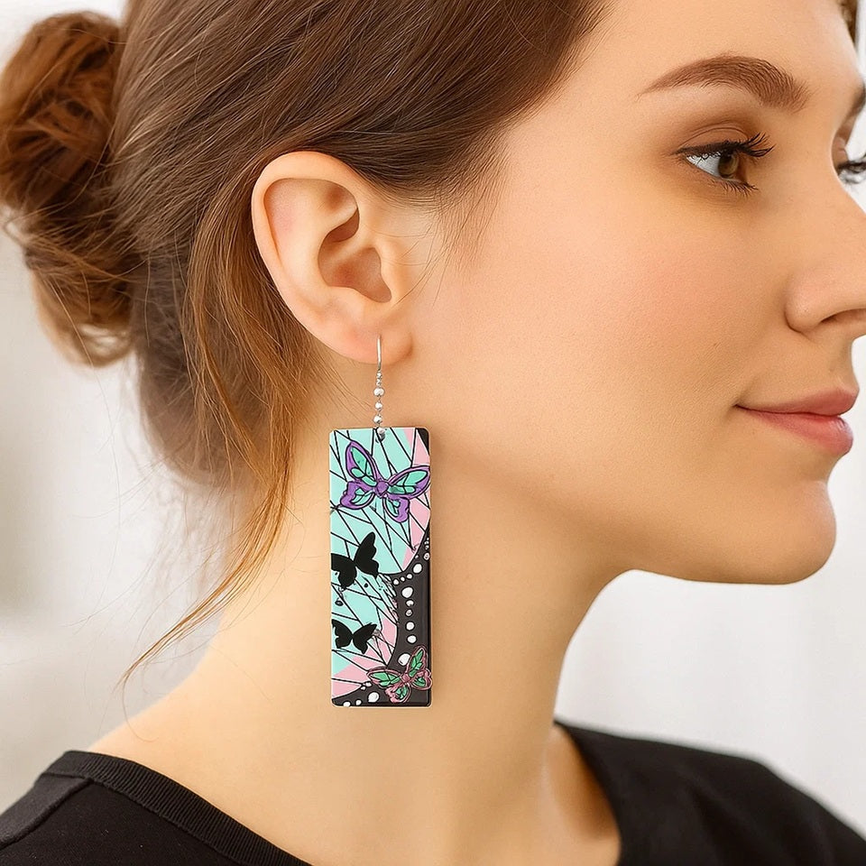 des boucles d'oreilles rectangulaires aux couleurs de Shinobu Kocho du manga Demon Slayer. On retrouve ses signes distinctifs comme les papillons