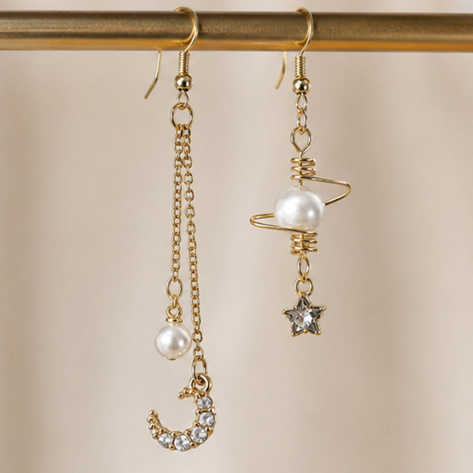 Boucles d’oreilles asymétriques dorées style kawaii céleste avec perles nacrées, lune strassée et étoile brillante. Design fin et élégant inspiré de l’univers spatial et féerique, parfait pour une tenue douce ou romantique.