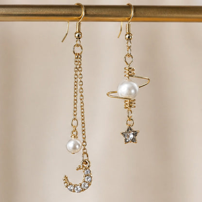 Boucles d’oreilles asymétriques dorées style kawaii céleste avec perles nacrées, lune strassée et étoile brillante. Design fin et élégant inspiré de l’univers spatial et féerique, parfait pour une tenue douce ou romantique.