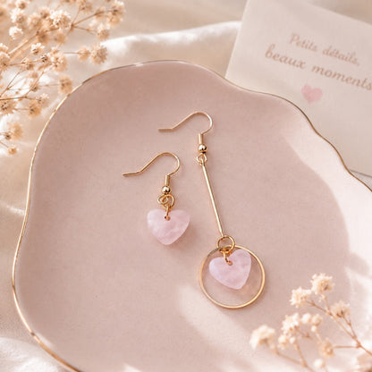 Mockup de bBasymétriques dorées avec pendentifs cœur rose nacré, présentées sur une assiette rose pastel dans une mise en scène élégante et romantique, idéale pour une boutique de bijoux kawaii.