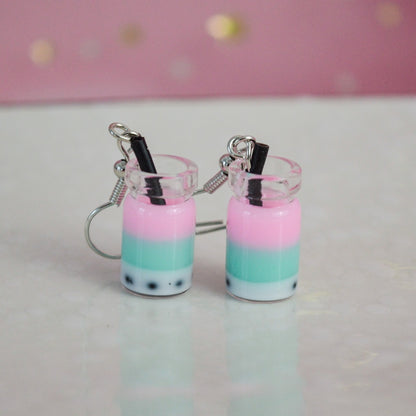 des boucles d'oreilles en forme de bubble tea de couleurs différentes. Certaines sont pailletées. Elles ont une paille pour plus de réalisme.