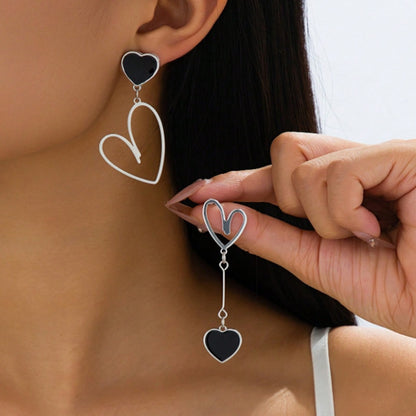 une paire de boucles d'oreilles asymétriques en forme de gros coeurs noirs pour un look romantique et mignon
