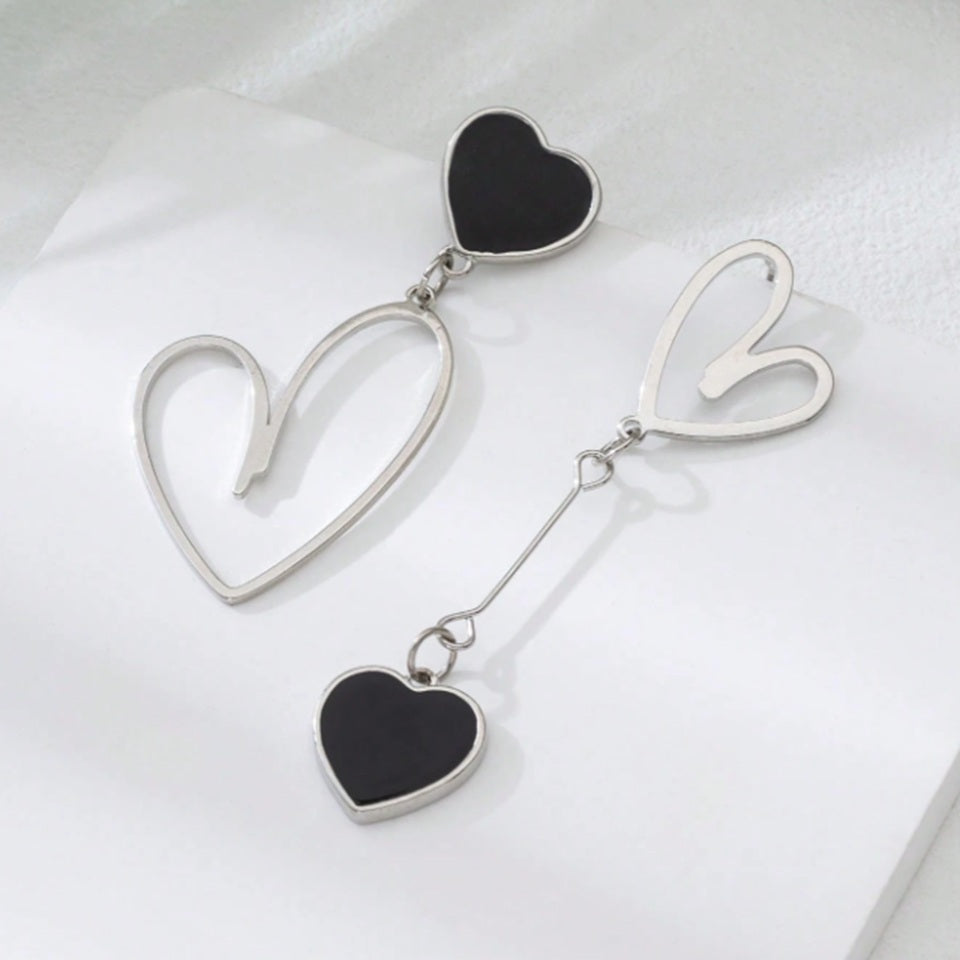 une paire de boucles d'oreilles asymétriques en forme de gros coeurs noirs pour un look romantique et mignon