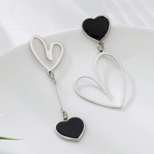 une paire de boucles d'oreilles asymétriques en forme de gros coeurs noirs pour un look romantique et mignon