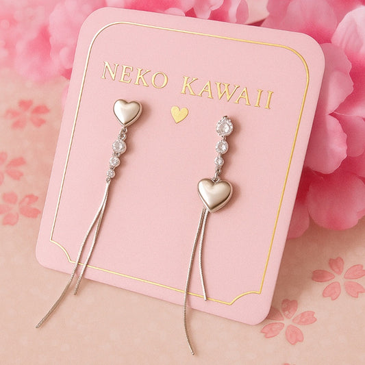 des boucles d'oreilles asymétriques et argentées en forme de cœurs. De jolis strass brillants viennent s'y ajouter ainsi que des chainettes. 