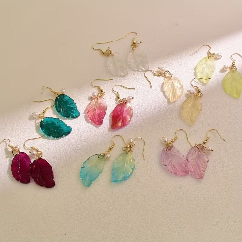 de jolies paires de boucles d'oreilles en forme de petites feuilles transparentes et colorées. Ornées d'une perle blanches, elles sont élégantes et rappellent avec douceur et légèreté l'automne.