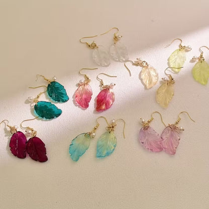 de jolies paires de boucles d'oreilles en forme de petites feuilles transparentes et colorées. Ornées d'une perle blanches, elles sont élégantes et rappellent avec douceur et légèreté l'automne.