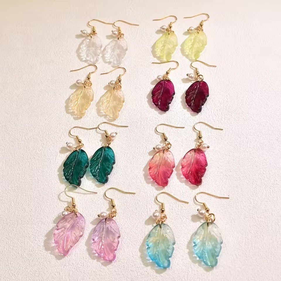 de jolies paires de boucles d'oreilles en forme de petites feuilles transparentes et colorées. Ornées d'une perle blanches, elles sont élégantes et rappellent avec douceur et légèreté l'automne.