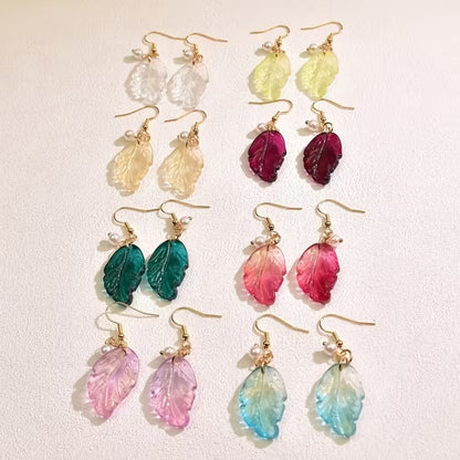 de jolies paires de boucles d'oreilles en forme de petites feuilles transparentes et colorées. Ornées d'une perle blanches, elles sont élégantes et rappellent avec douceur et légèreté l'automne.