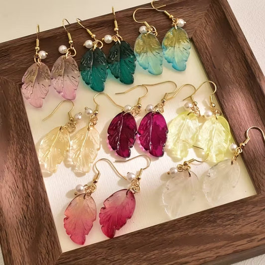 de jolies paires de boucles d'oreilles en forme de petites feuilles transparentes et colorées. Ornées d'une perle blanches, elles sont élégantes et rappellent avec douceur et légèreté l'automne.