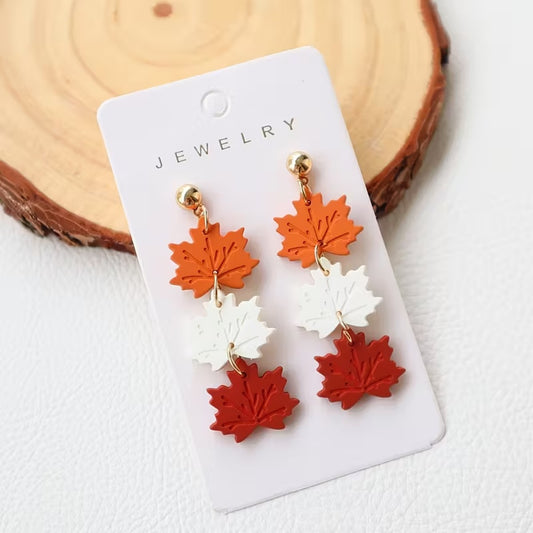 des boucles d'oreilles composées de trois feuilles d'érable orange, blanche et rouge. Elles rappellent l'automne et ses couleurs chatoyantes. En acrylique, elles sont légères et confortables à porter.