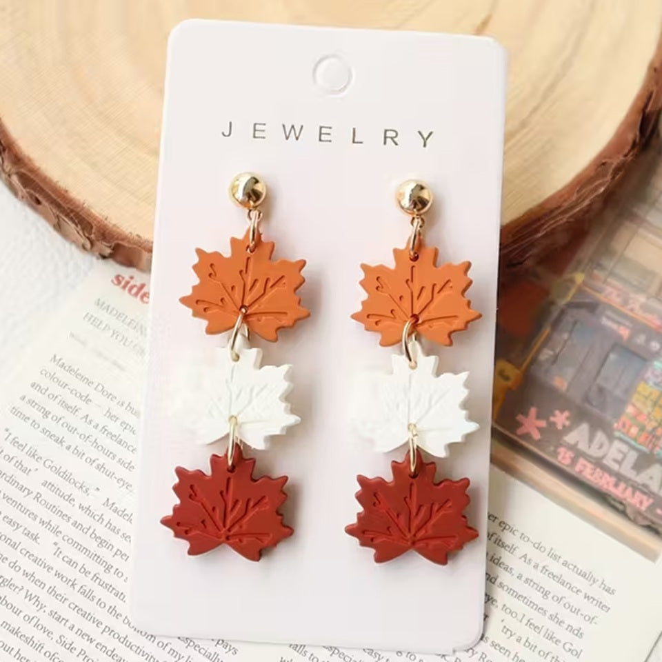 des boucles d'oreilles composées de trois feuilles d'érable orange, blanche et rouge. Elles rappellent l'automne et ses couleurs chatoyantes. En acrylique, elles sont légères et confortables à porter.