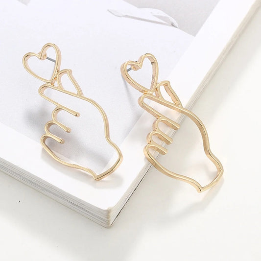 une paire de boucles d'oreilles original et pleine d'amour en forme de main qui forment un coeur: le finger heart coréen.