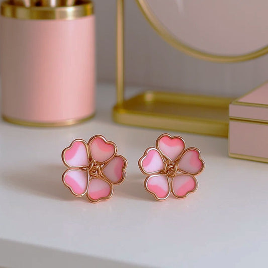 une paire de boucles d'oreilles rose gold en forme de petites fleurs de sakura roses et blanches. L'ensemble est poétique et romantique.