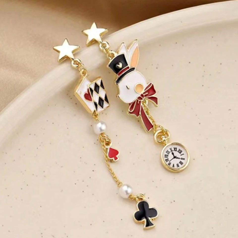 une paire de boucles d'oreilles asymétriques inspirés de l'univers d'Alice aux pays des merveilles. D'un côté un lapin blanc et sa montre, de l'autre, des cartes à jouer et des perles blanches.