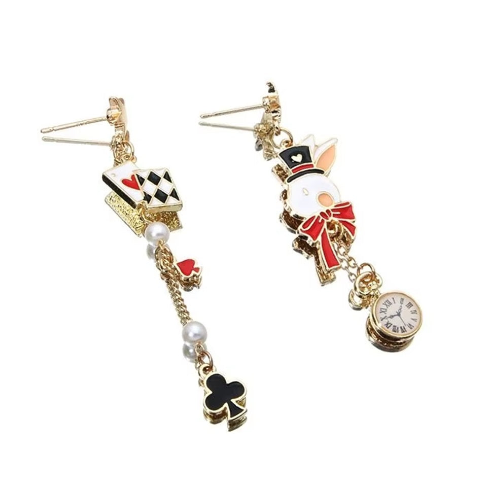 une paire de boucles d'oreilles asymétriques inspirés de l'univers d'Alice aux pays des merveilles. D'un côté un lapin blanc et sa montre, de l'autre, des cartes à jouer et des perles blanches.