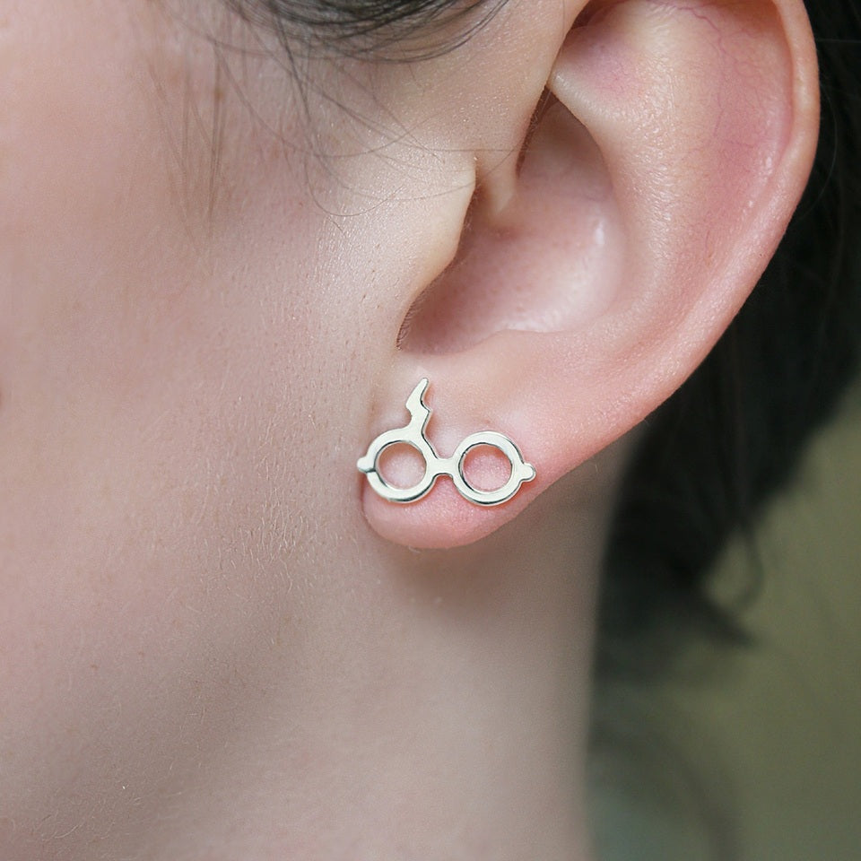 des boucles d'oreilles en forme des lunettes du sorcier le plus célèbre de Poudlard: Harry Potter. On retrouve également sa cicatrice.