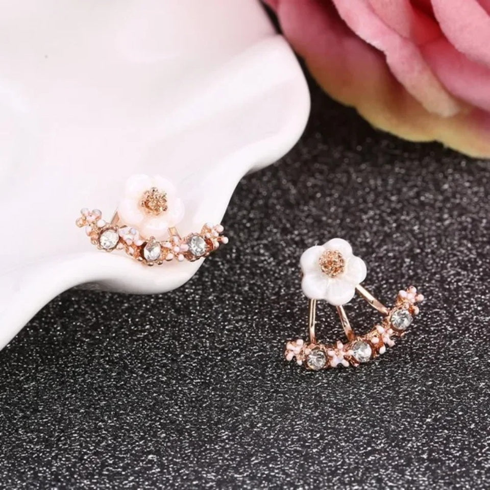 une paire de boucles d'oreilles en forme d'une jolie fleur blanche ornée de strass. Elle épouse le lobe de l'oreille avec délicatesse