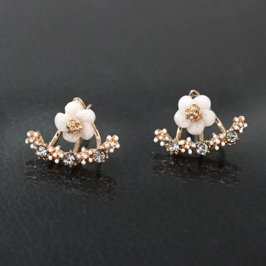 une paire de boucles d'oreilles en forme d'une jolie fleur blanche ornée de strass. Elle épouse le lobe de l'oreille avec délicatesse