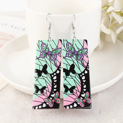 des boucles d'oreilles rectangulaires aux couleurs de Shinobu Kocho du manga Demon Slayer. On retrouve ses signes distinctifs comme les papillons