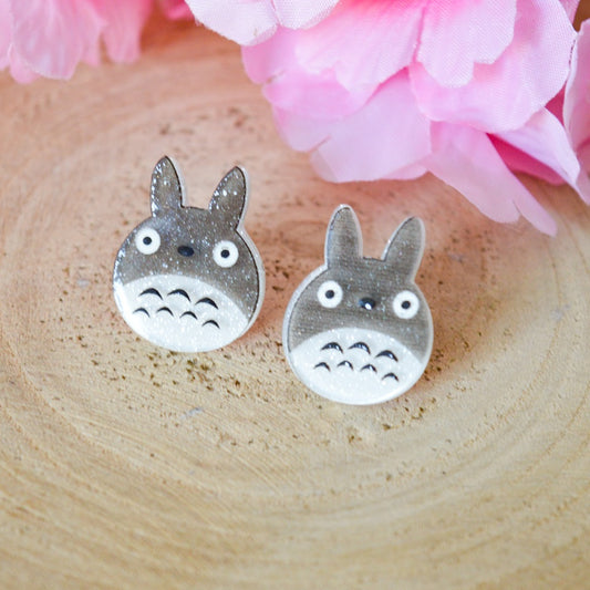 une paire de boucles d'oreilles en acrylique représentant Totoro sous une forme chibi et tout en paillettes.