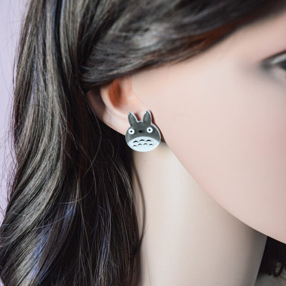 une paire de boucles d'oreilles en acrylique représentant Totoro sous une forme chibi et tout en paillettes.