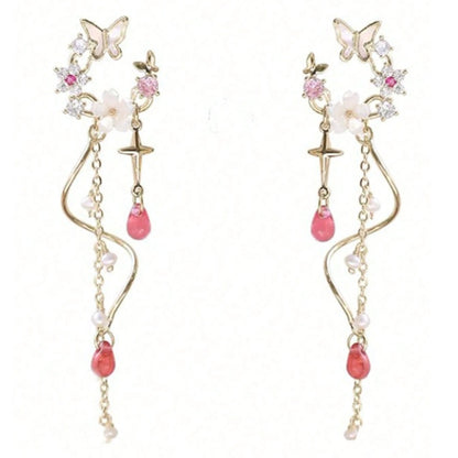 une paire de boucles d'oreilles composées d'une ronde de fleurs blanches et de strass roses, d'un joli papillon blanc, d'où pendent une chaine dorée et une tige torsadée ainsi qu'une douce étoilée dorée. Au bout, il y a des perles en forme de goutte rose. l'ensemble est poétique et féminin.