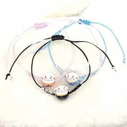 un bracelet en tissu en forme d'un maneki neko coloré. Symbole de chance, de bonne fortune, il est inspiré du style japonais