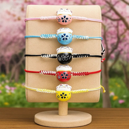 un bracelet en tissu en forme d'un maneki neko coloré. Symbole de chance, de bonne fortune, il est inspiré du style japonais