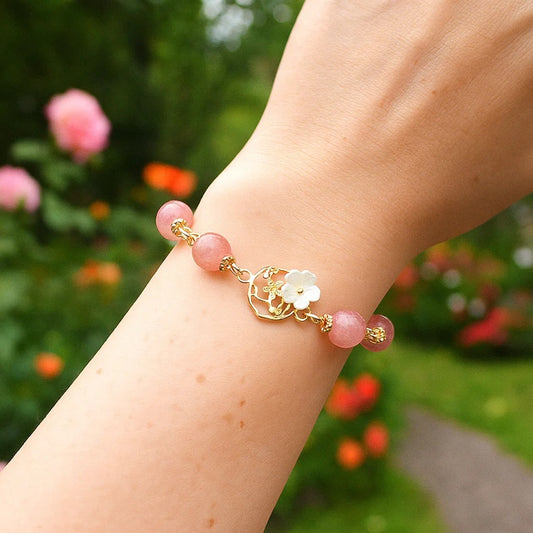 un superbe bracelet dorée de perles roses et d'une breloque fleur de sakura. L'ensemble est poétique, romantique.