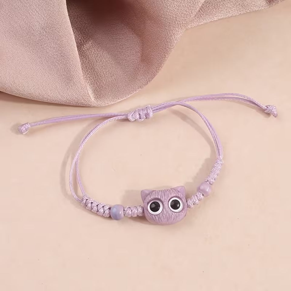 De jolis bracelets en corde tressée avec une breloque en forme de tête de chat colorée avec de gros yeux ronds brillants