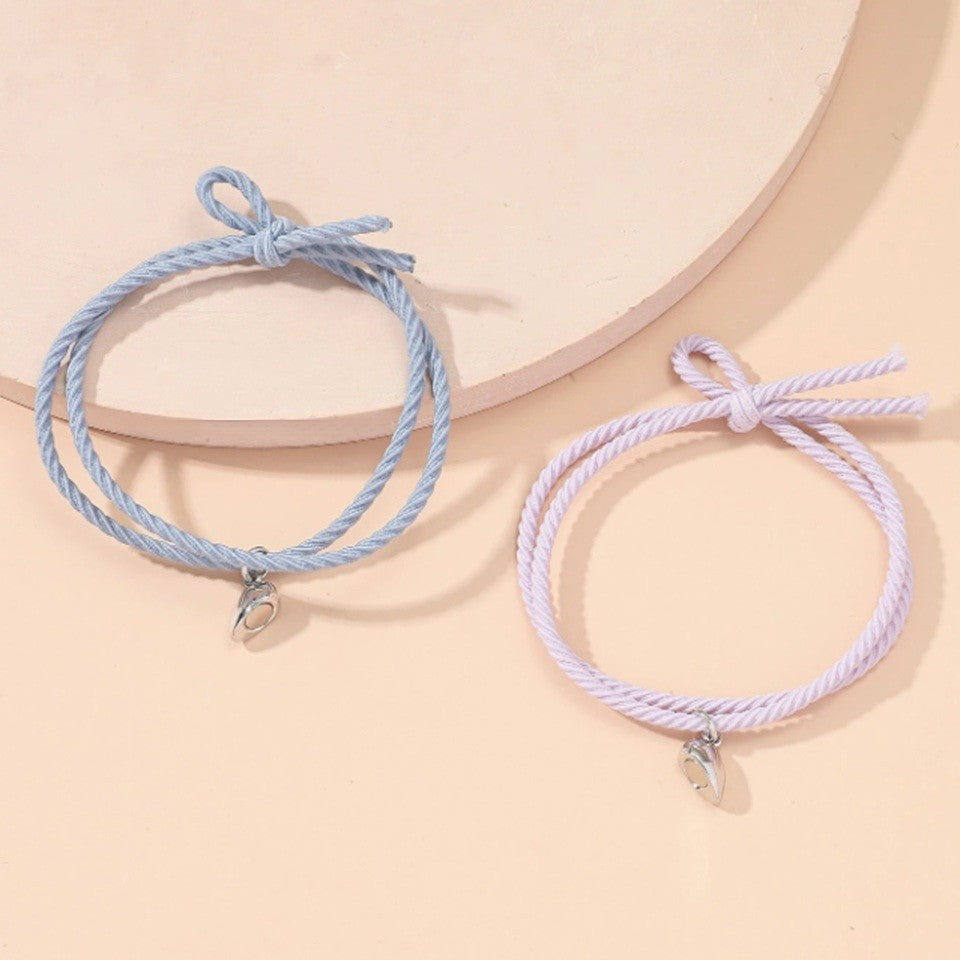 deux bracelets au cordon bleu et rose qui possède chacun une moitié de coeur aimanté. Quand ils sont réunis, le coeur se reforme.