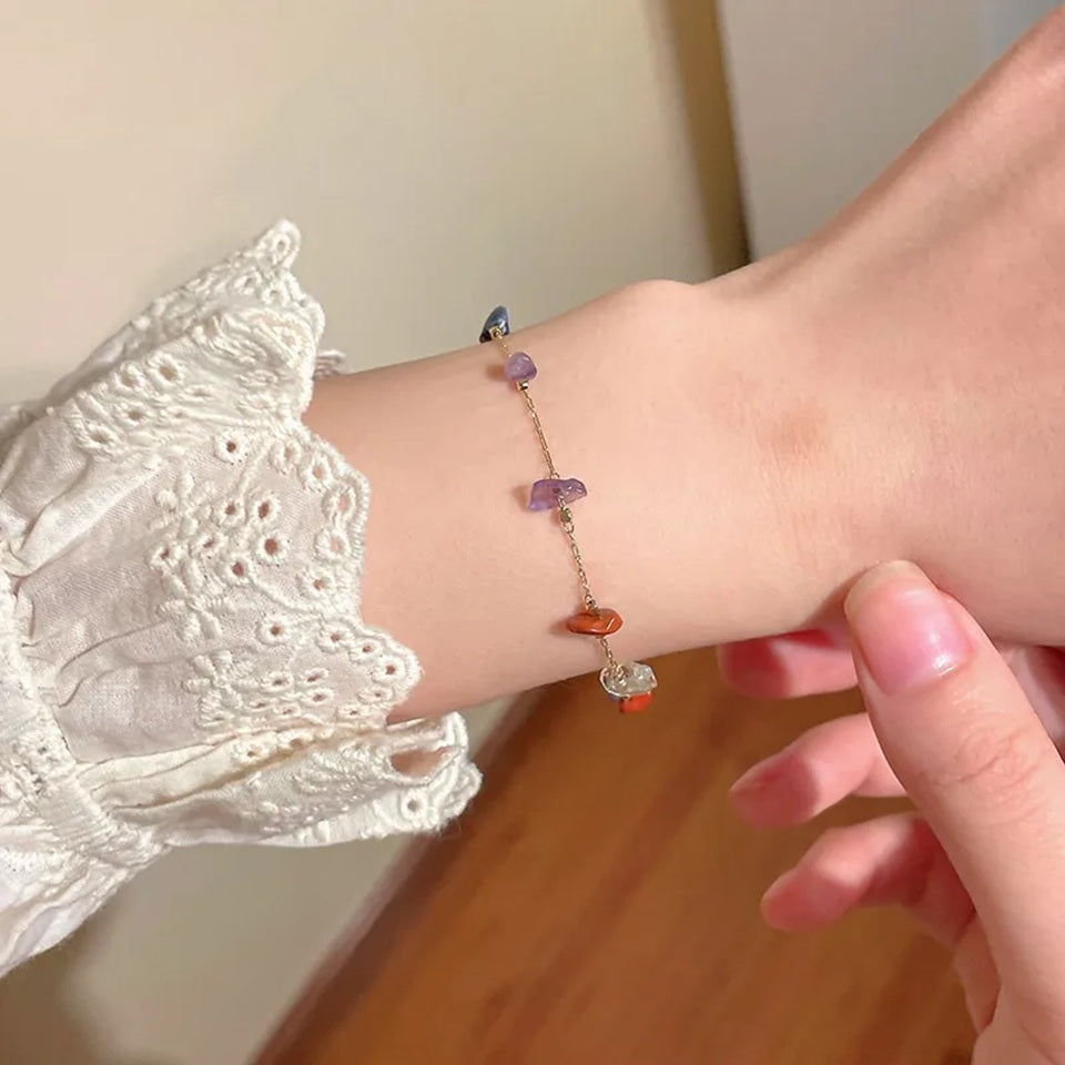 gros plan sur un bracelet doré composé de pierres de couleurs, porté au poignet par une femme.
