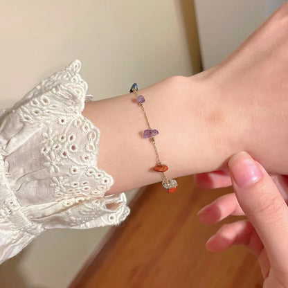 gros plan sur un bracelet doré composé de pierres de couleurs, porté au poignet par une femme.