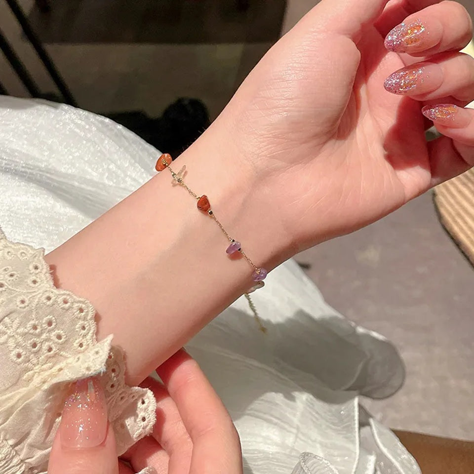gros plan sur un bracelet doré composé de pierres de couleurs, porté au poignet par une femme.