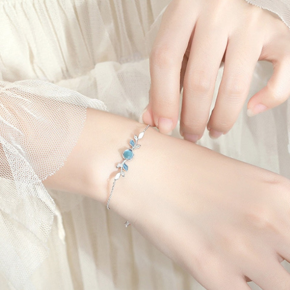 un superbe bracelet argenté représentant de jolies feuilles argentées et bleues et une pierre de lune ronde aux reflets bleutés. Le bijou est élégant, fin et très féminin.