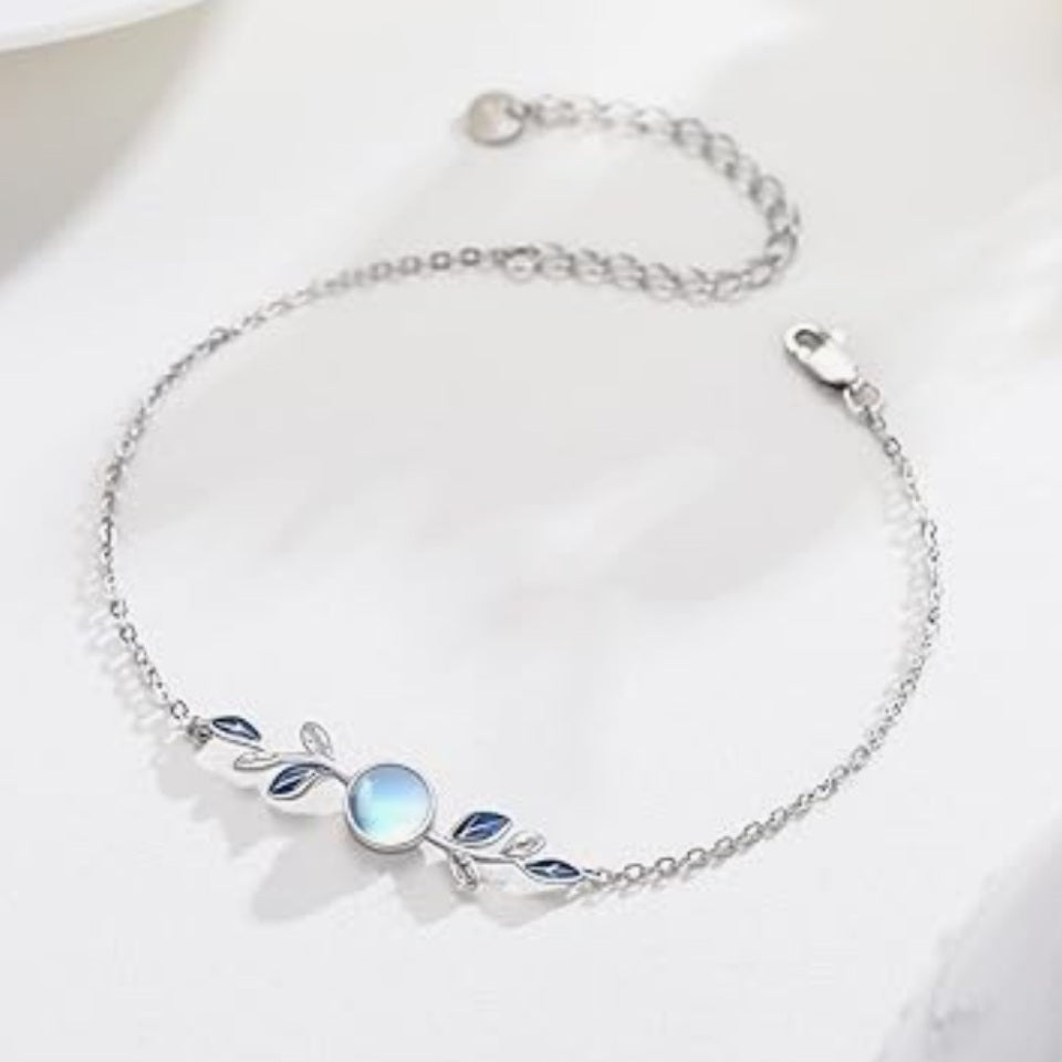 un superbe bracelet argenté représentant de jolies feuilles argentées et bleues et une pierre de lune ronde aux reflets bleutés. Le bijou est élégant, fin et très féminin.