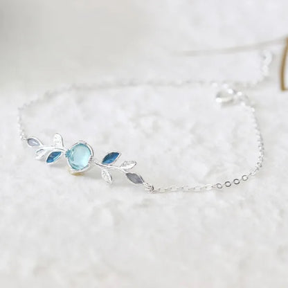 un superbe bracelet argenté représentant de jolies feuilles argentées et bleues et une pierre de lune ronde aux reflets bleutés. Le bijou est élégant, fin et très féminin.