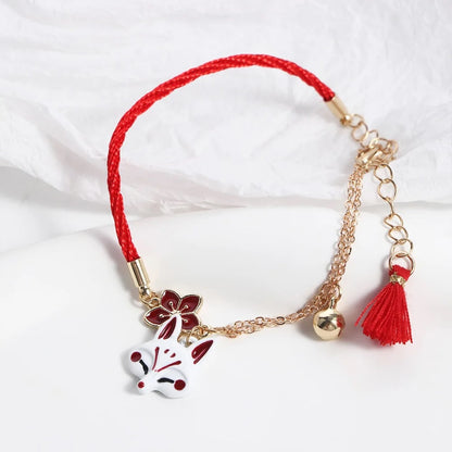 un bracelet kistune, une fleur de sakura rouge, une clochette adorable, le tout en coloris rouge et blanc. Harmonie parfaite. Inspiration du Japon