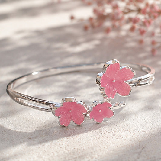 un bracelet argenté de taille réglable composé de trois fleurs de sakura rose. Design féminin, floral et romantique 