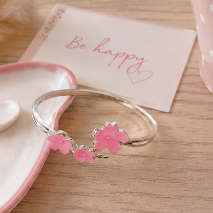 un bracelet argenté de taille réglable composé de trois fleurs de sakura rose. Design féminin, floral et romantique 