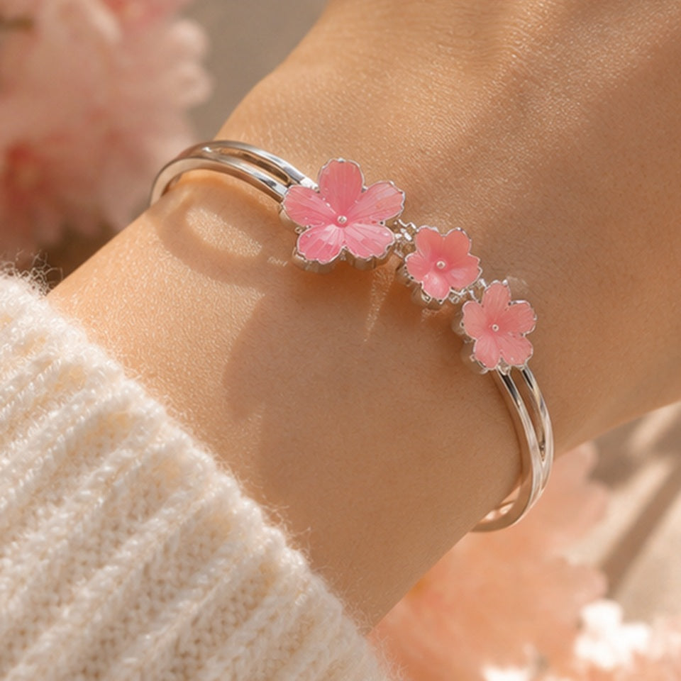 un bracelet argenté de taille réglable composé de trois fleurs de sakura rose. Design féminin, floral et romantique 