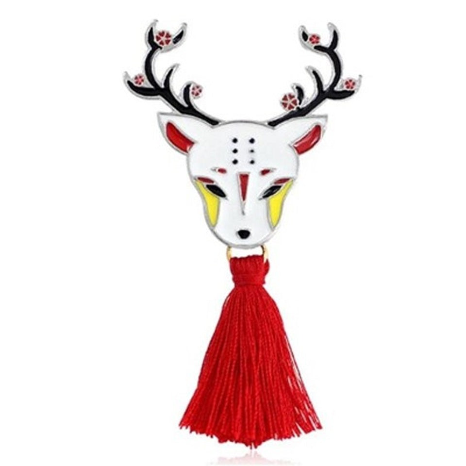 une broche en métal en forme d'un cerf représenté de façon onirique selon le folklore japonais. Il est élégant avec ces bois fleuris et son pompon rouge.